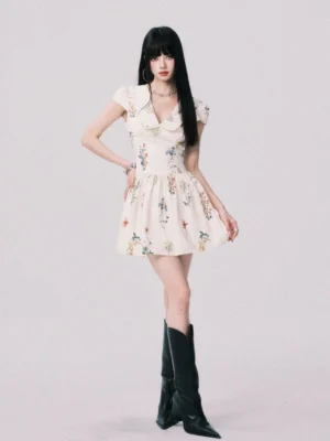 Cream wildflower floral collared mini dress shown in a full-body three-quarter front view with fitted waist, flared A-line skirt, cap sleeves, and black knee-high boots