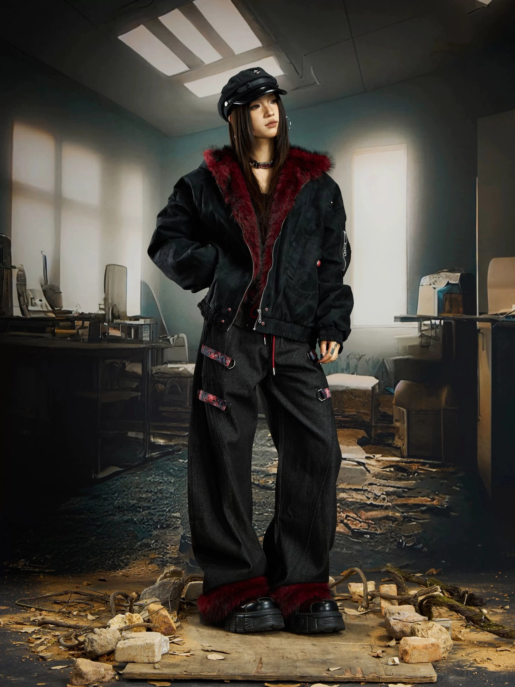 Three quarter view of oversized black gothic streetwear bomber jacket with deep red faux fur hood trim on female model