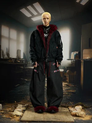 Male model in black gender neutral gothic bomber jacket with burgundy faux fur hood trim and matching dark cargo streetwear outfit