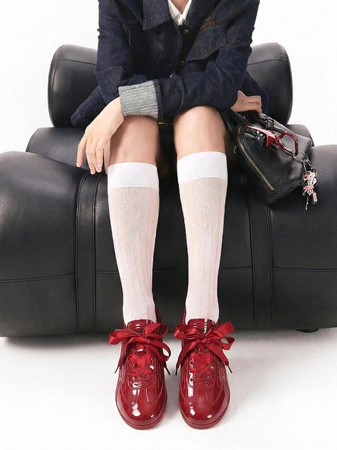 Female model styling crimson red gloss retro runner sneakers with knee-high socks and dark denim streetwear