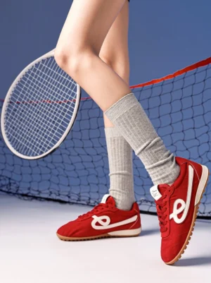Crimson quilted gum sole retro sneakers worn with grey crew socks beside a tennis net