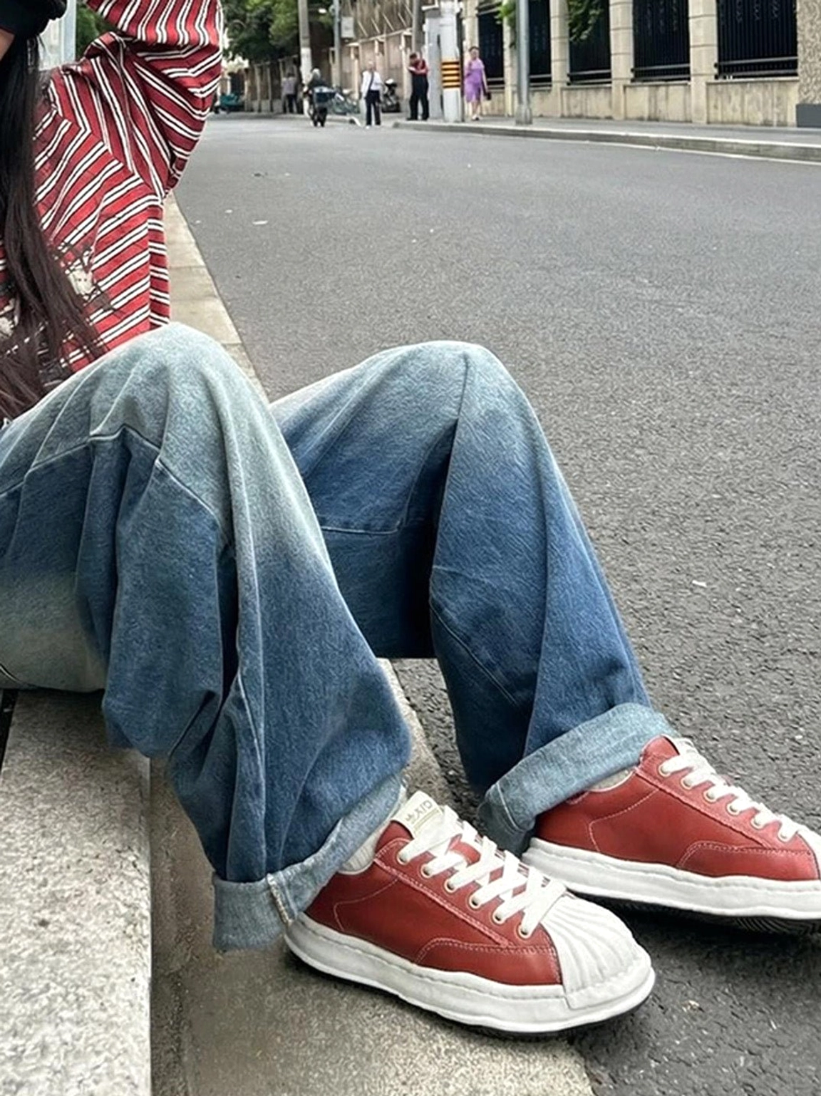 Crimson red molded-toe sneakers worn with rolled blue jeans and a striped top in a casual Seoul-inspired street look