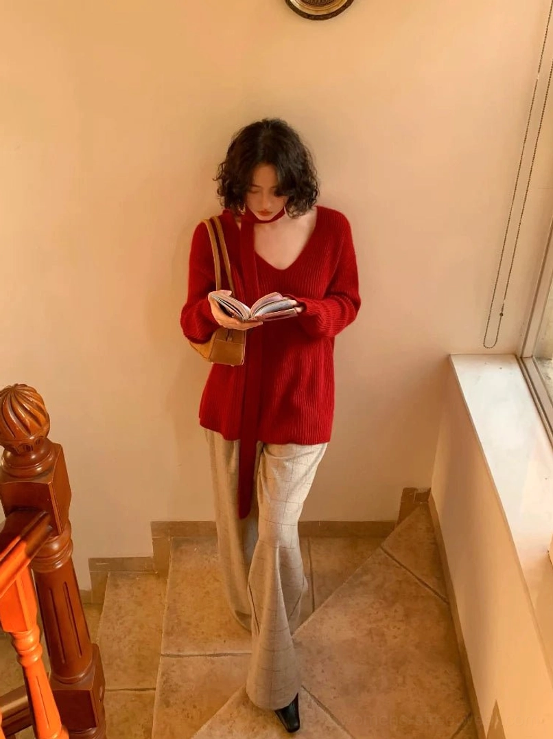 Crimson red ribbed V-neck sweater with matching skinny scarf tie styled with beige wide-leg trousers