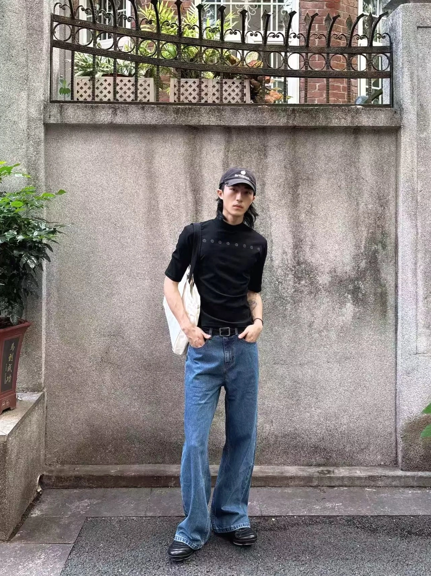 Front and side styling view of a black slim fit mock neck streetwear shirt with a bold blade graphic visible on the back