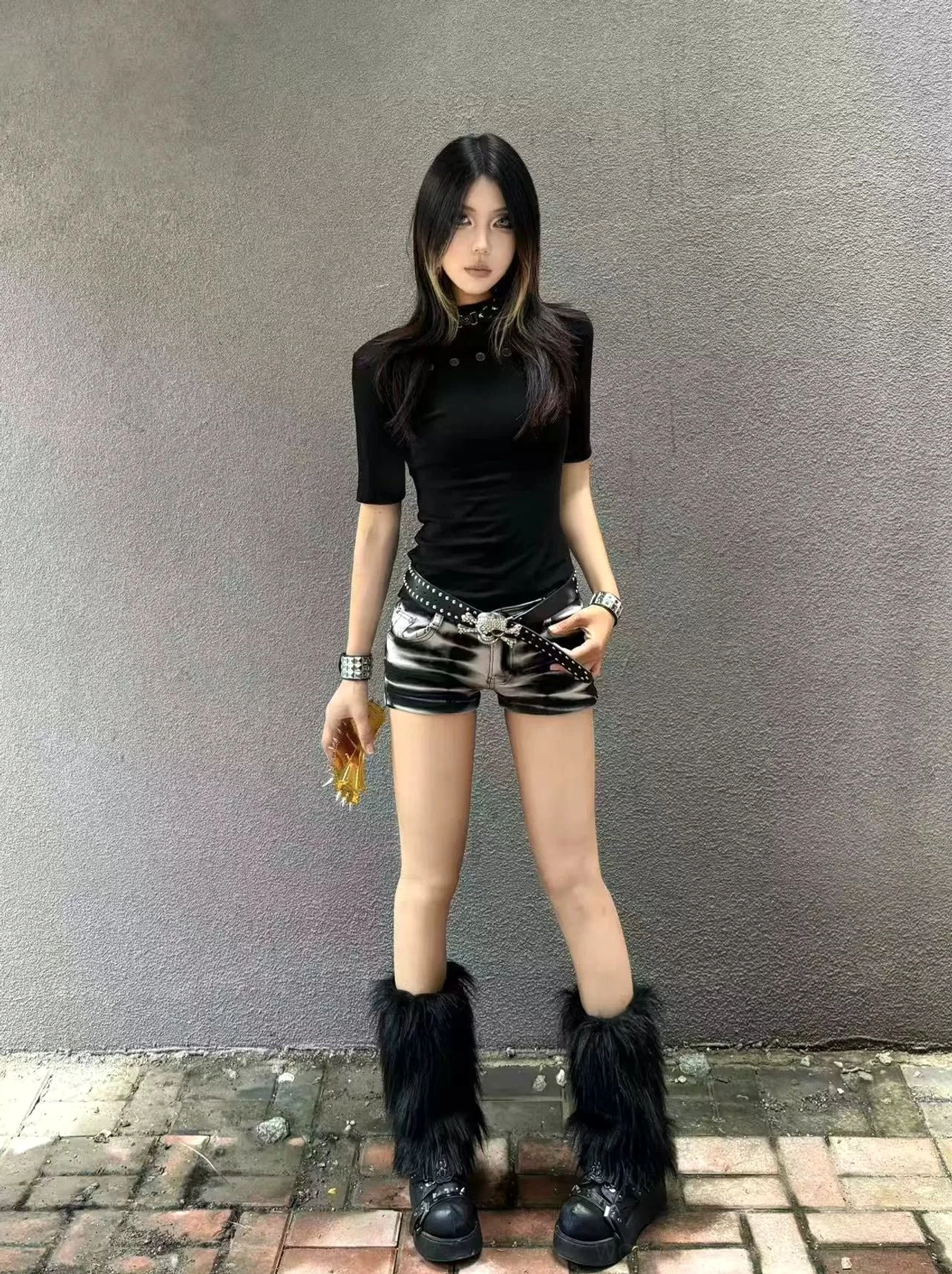 Front view of a fitted black women's mock neck streetwear tee styled with low rise shorts and fuzzy platform boots