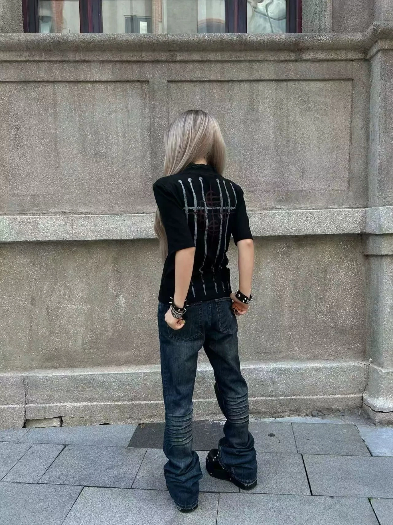 Back view of a black mock neck streetwear tee showing vertical distressed white blade graphics and crimson sigil artwork