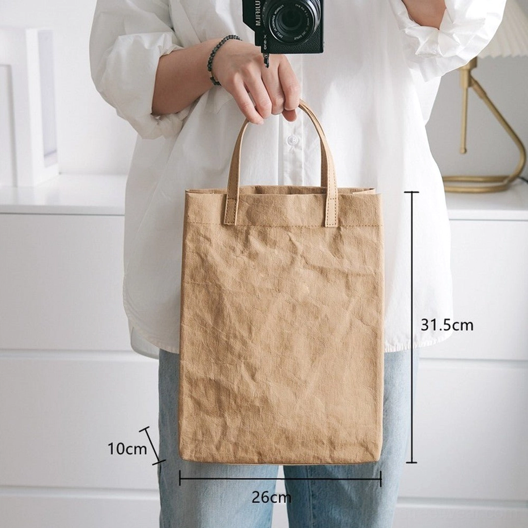 Large tan crinkled kraft paper effect cotton tote bag shown with size measurements in a casual daily outfit