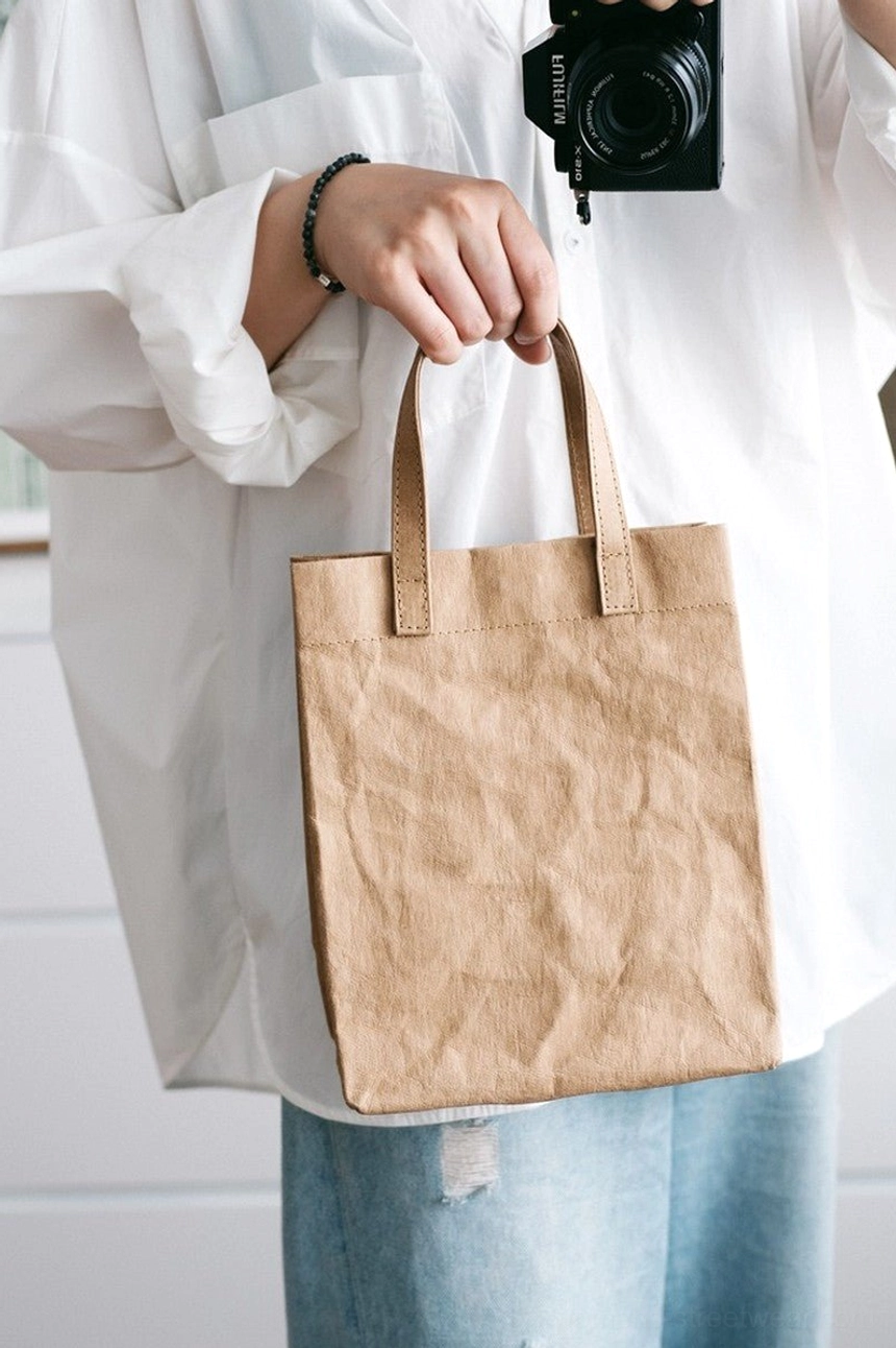 Tan kraft paper effect cotton tote bag carried with a white shirt and blue jeans for a minimalist Korean streetwear outfit
