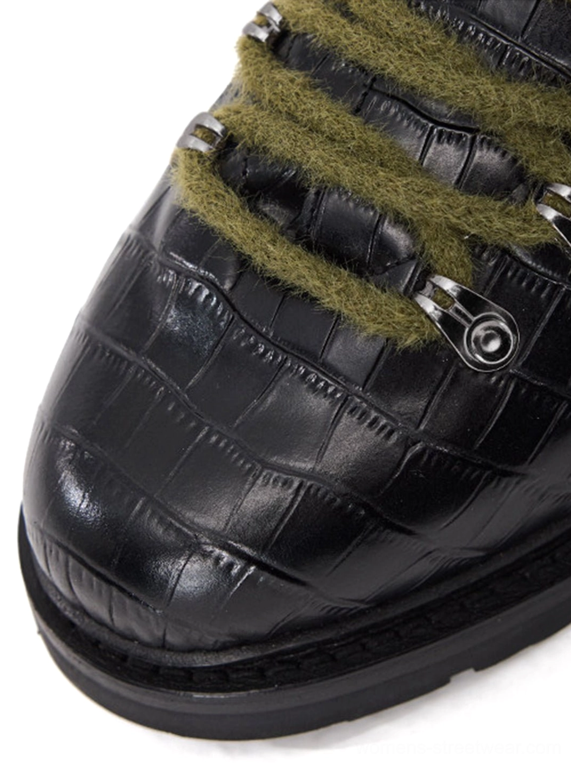 Close-up of glossy black crocodile embossed leather derby shoe toe with olive laces, silver eyelet, and thick sole border