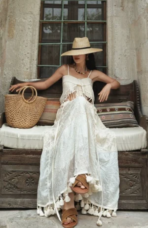 White crochet fringe maxi dress with crocheted bust detail and long tassel trim styled on a vintage outdoor bench
