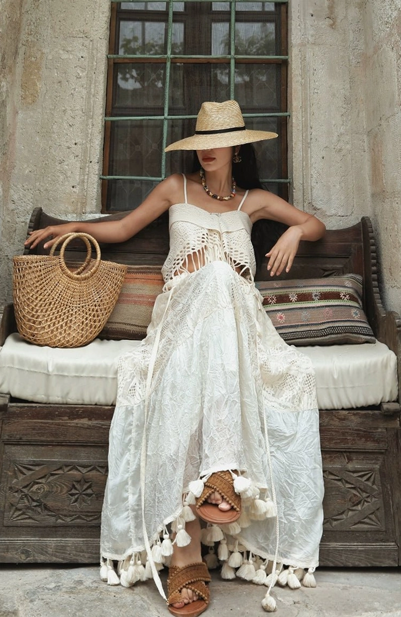 White crochet fringe maxi dress with crocheted bust detail and long tassel trim styled on a vintage outdoor bench