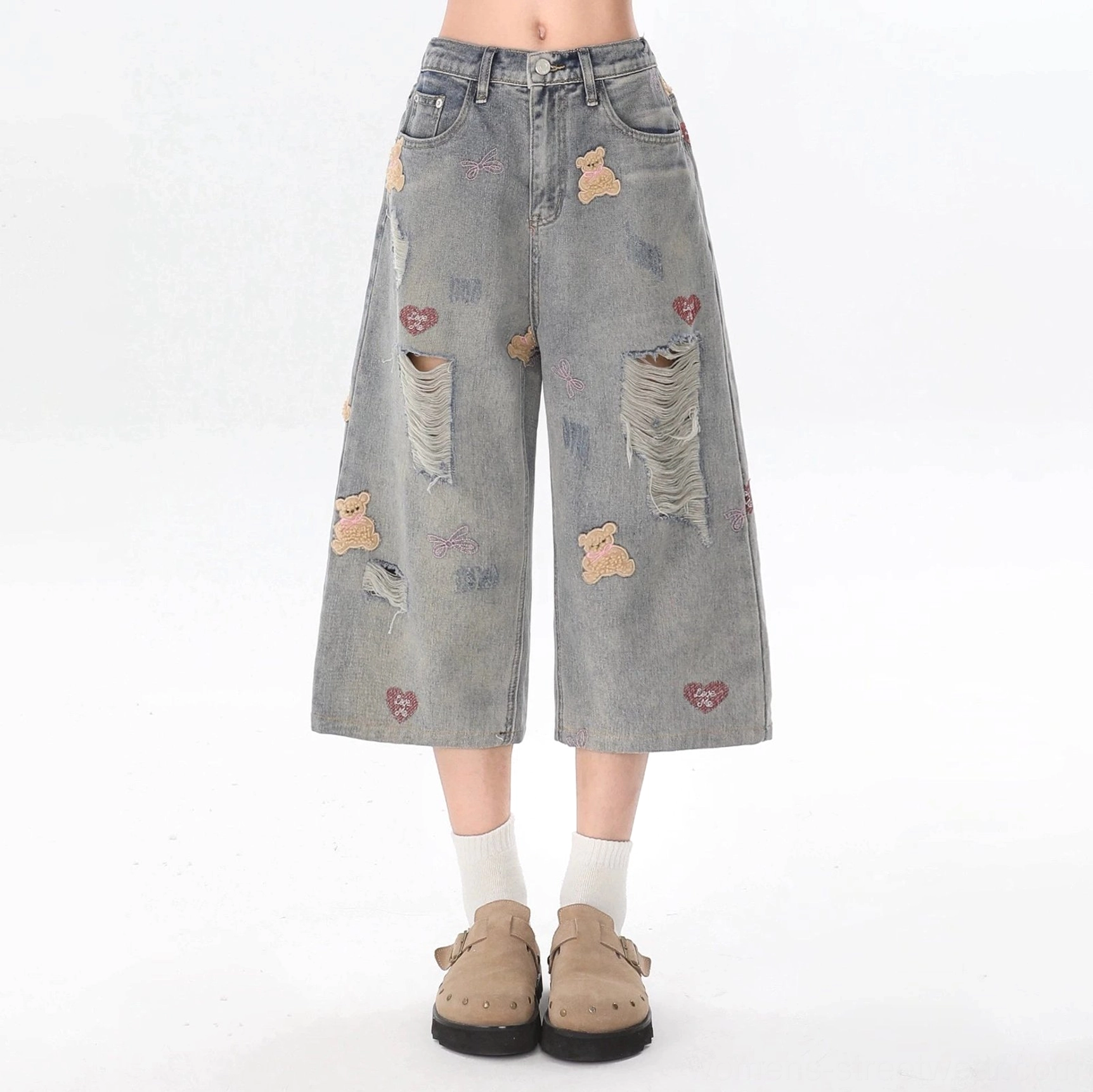 Cropped distressed wide-leg jeans with teddy bear embroidery, red heart motifs, large frayed holes, beige loafers, and white socks