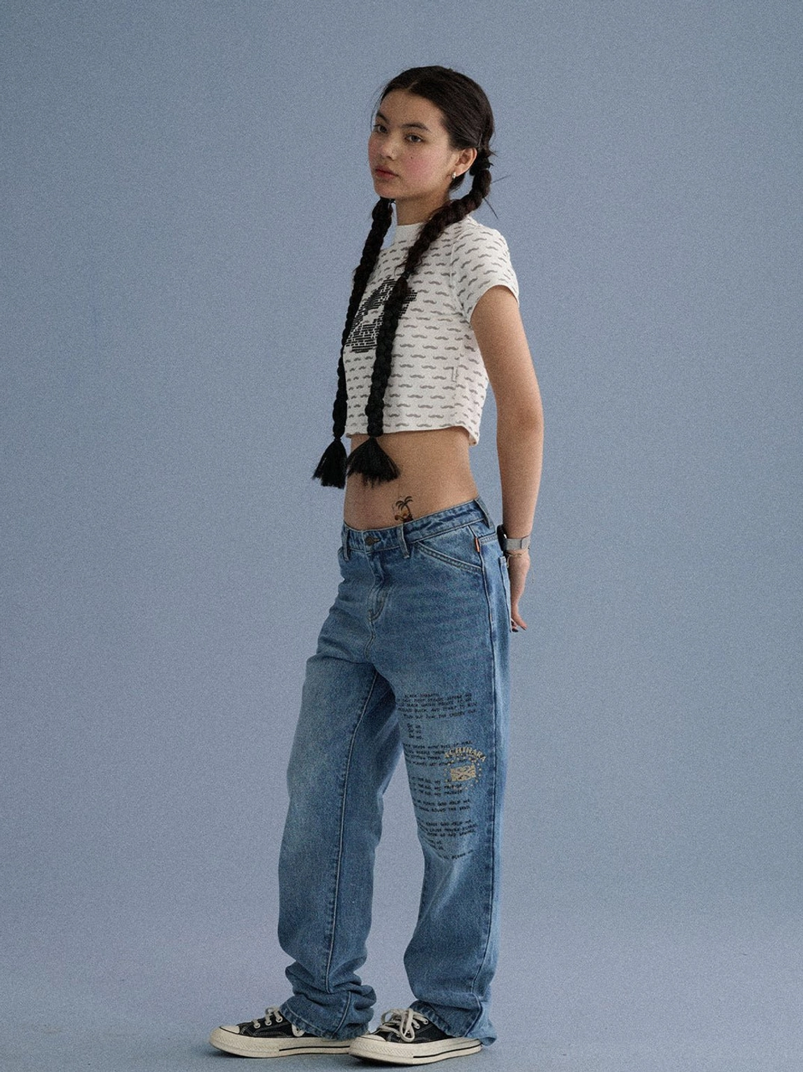 Three-quarter side view of a cropped mustache graphic tee with subtle line print and relaxed streetwear styling