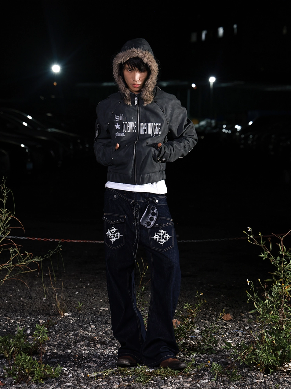 Cropped PU hooded jacket worn with the hood up, brown faux fur trim, graphic prints, and dark urban streetwear styling