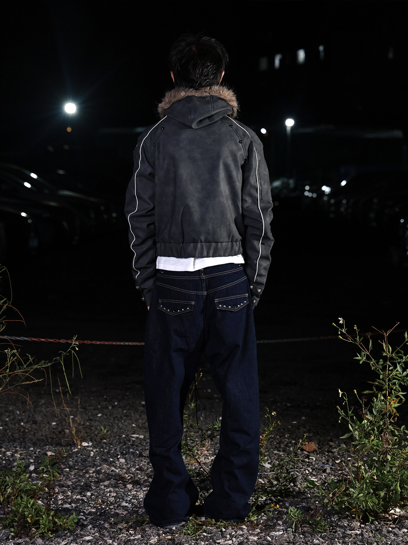 Back medium view showing the cropped hem, faux fur hood collar, and contrast sleeve piping on a PU streetwear jacket
