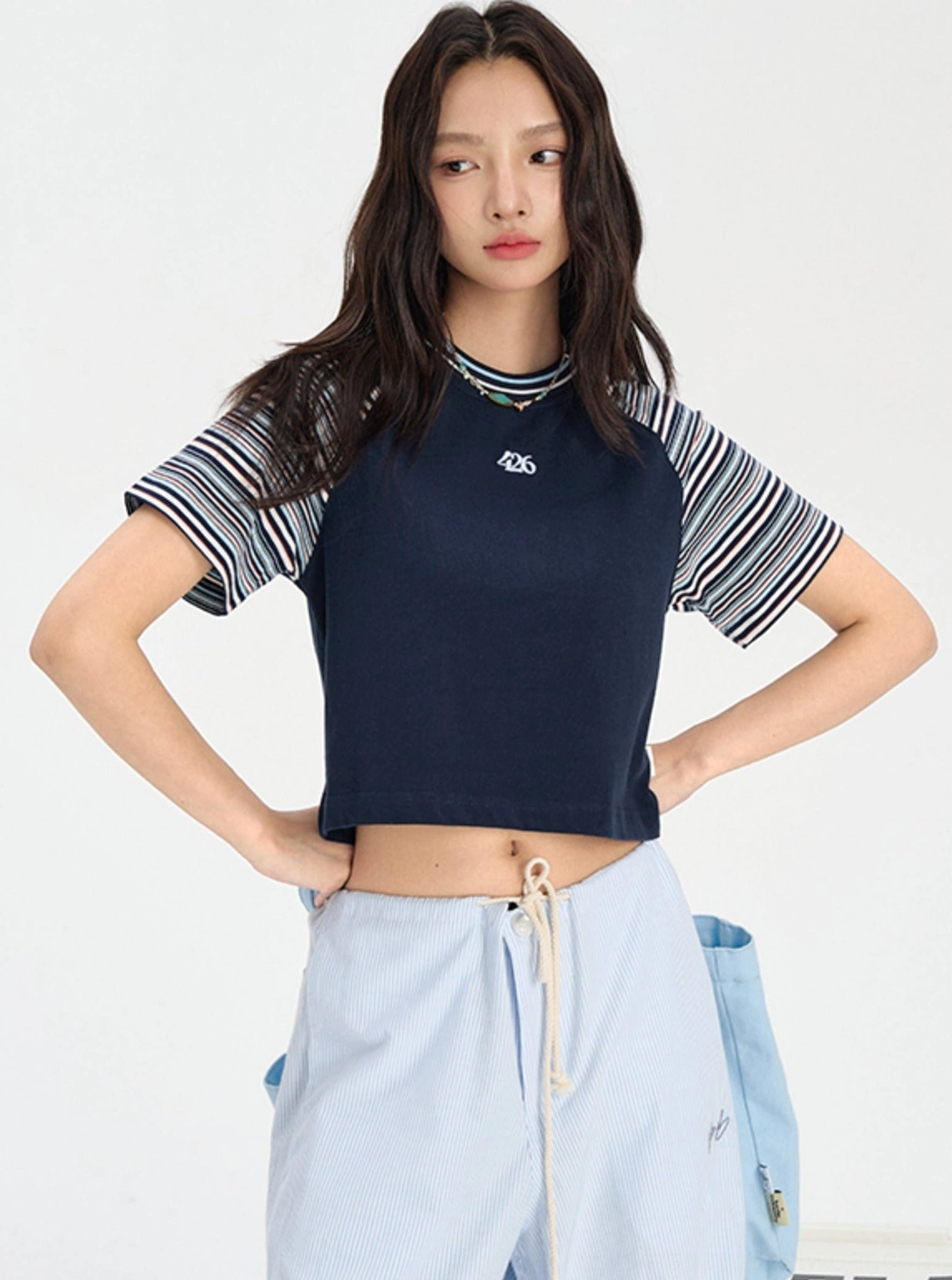 Cropped rainbow stripe raglan baby tee showing sporty contrast sleeve construction