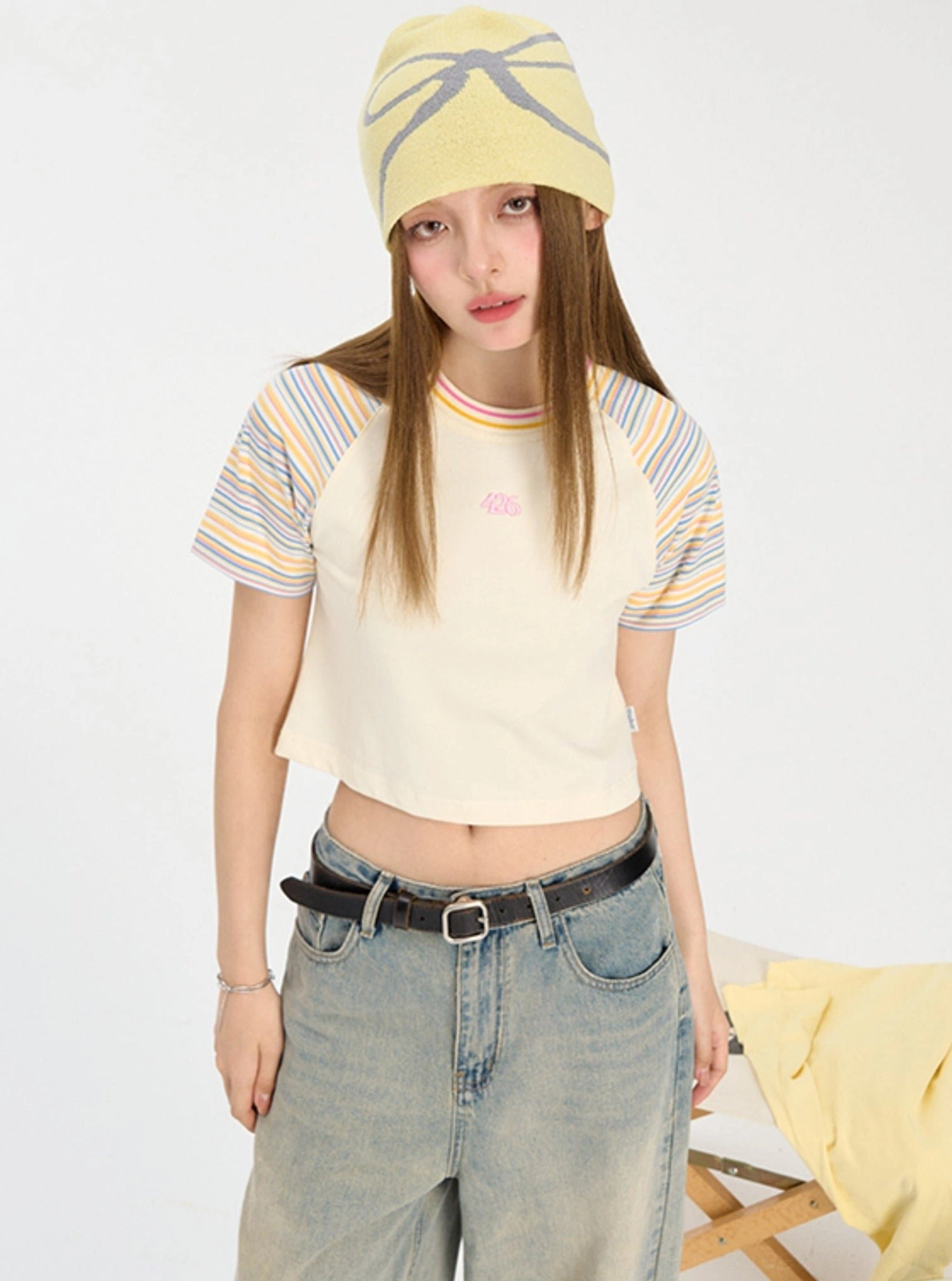 Full body view of yellow cropped striped raglan tee paired with wide leg denim for Y2K streetwear