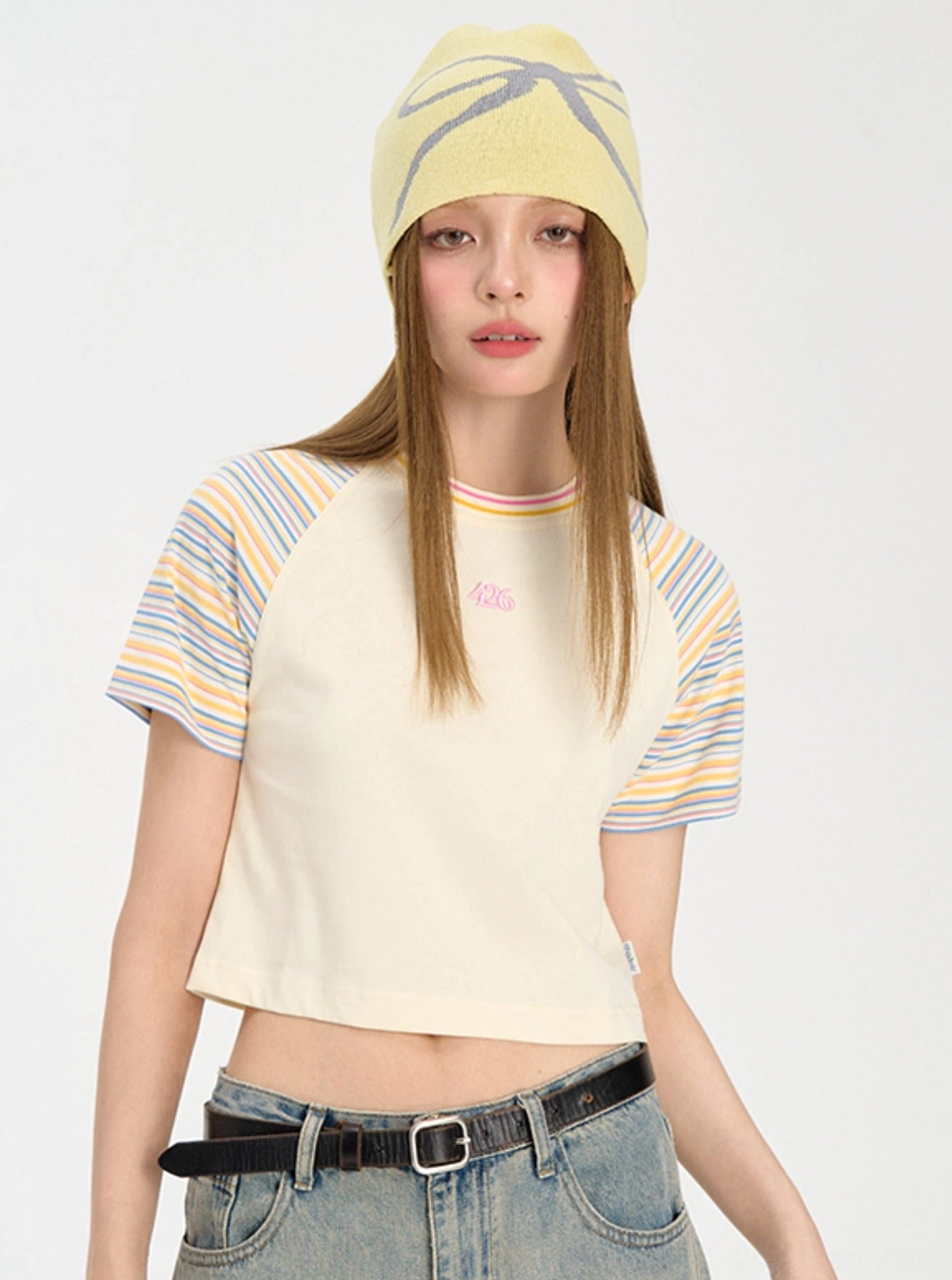 Yellow cropped rainbow stripe raglan baby tee styled with low rise denim in a Y2K streetwear outfit