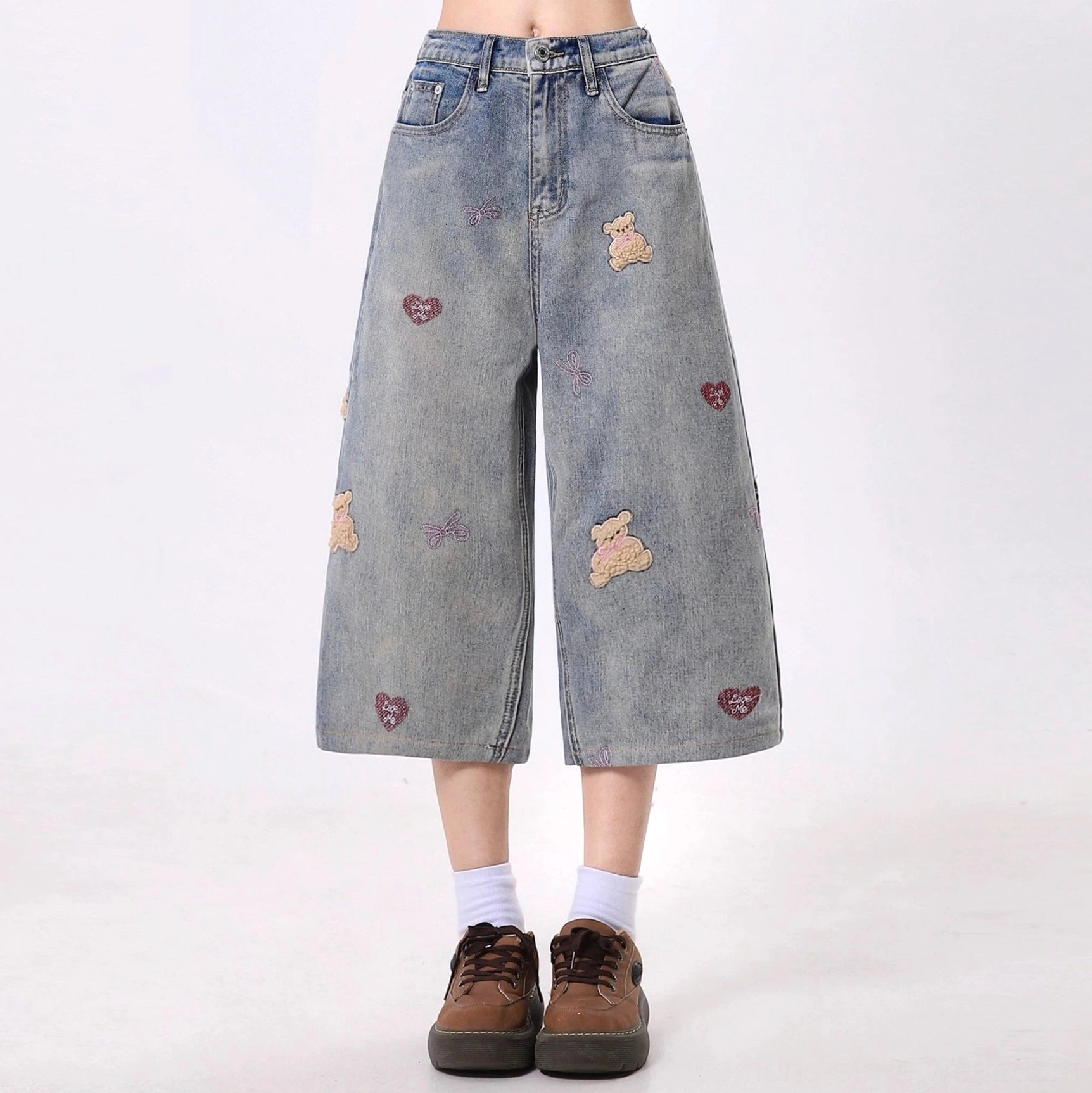 Cropped wide-leg vintage washed blue jeans with teddy bear and red heart embroidery styled with white socks and brown loafers