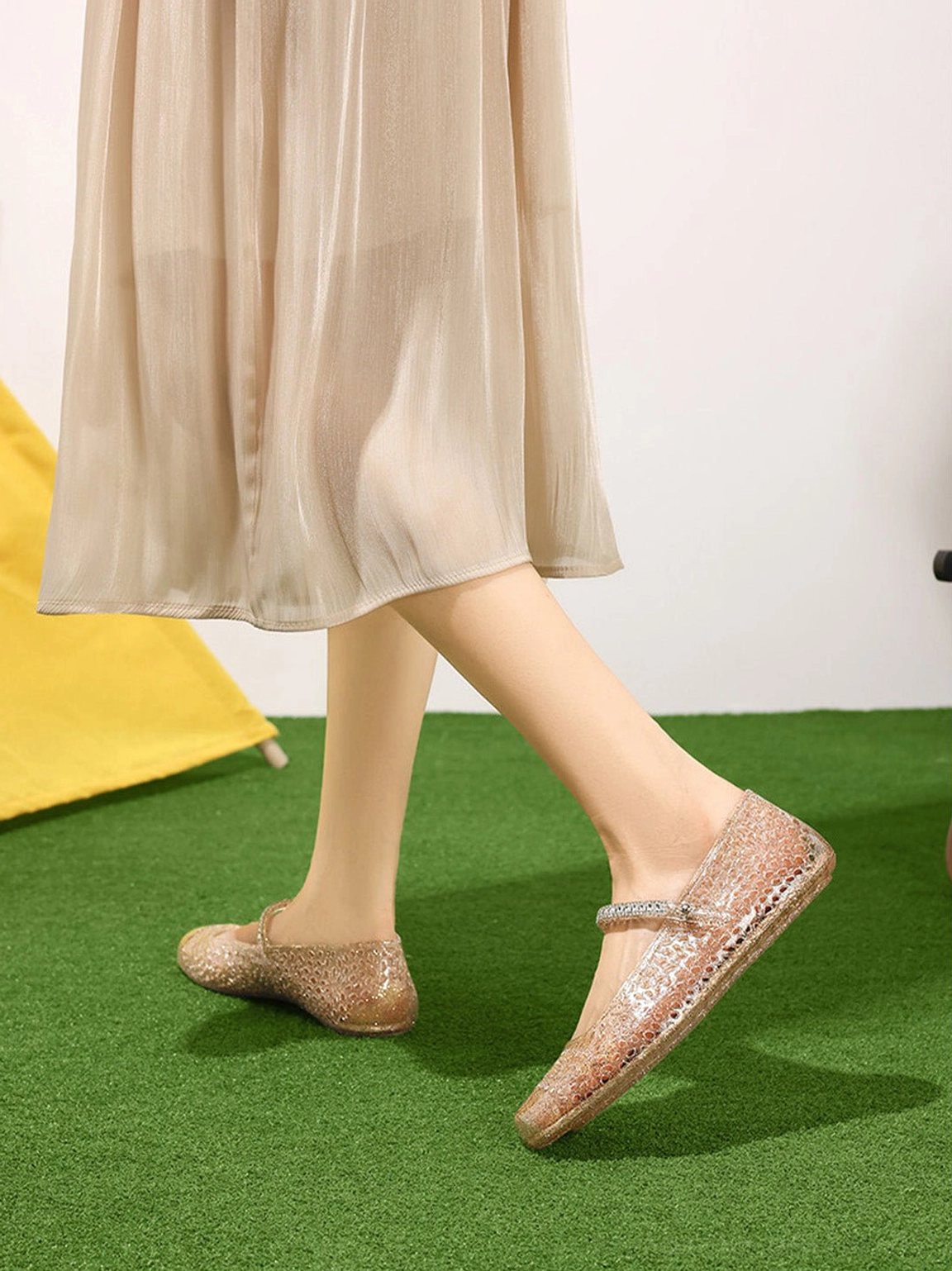 Woman walking in champagne gold glitter jelly Mary Jane ballet flats with beige midi skirt