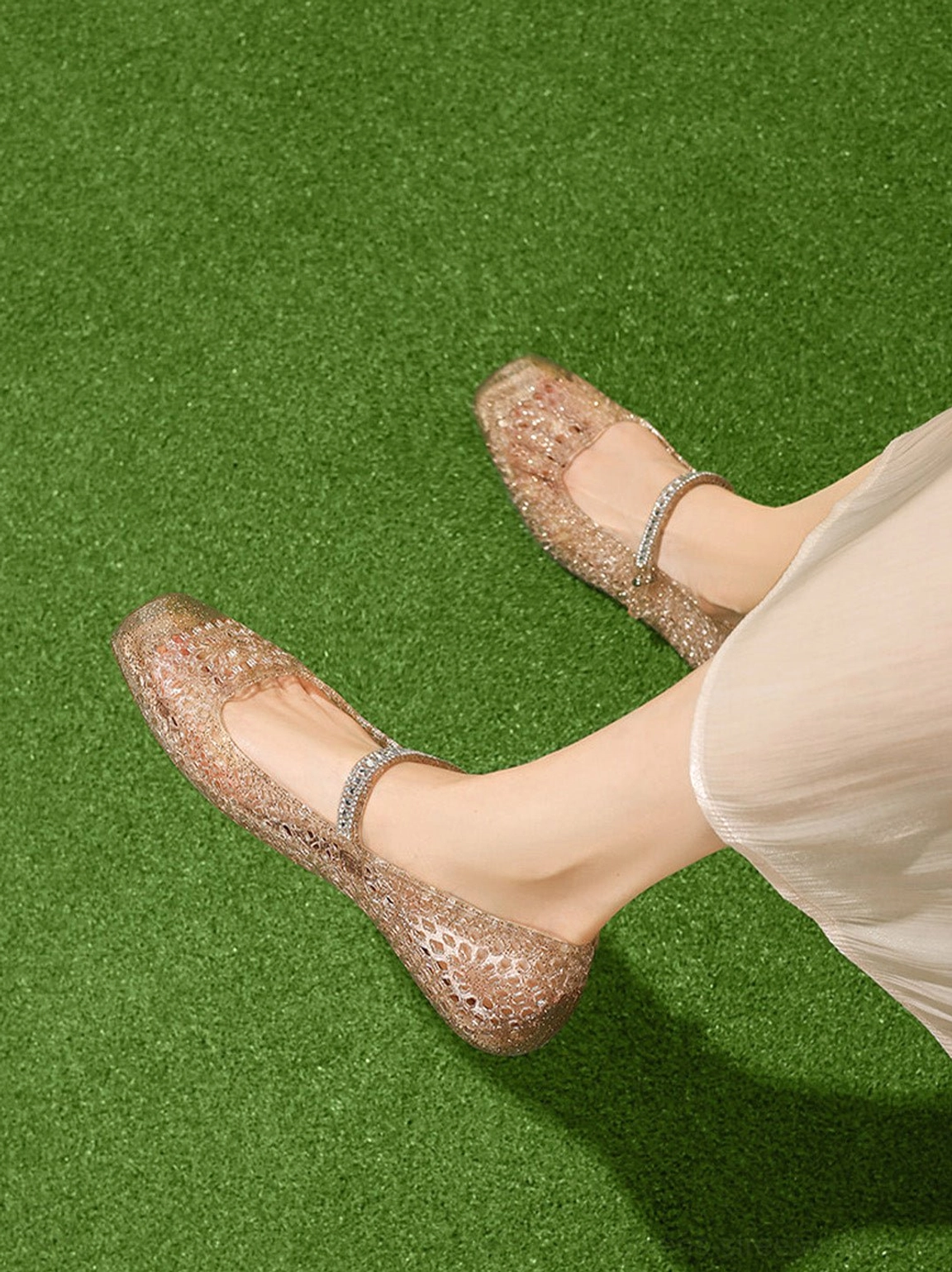 Top view of champagne gold crystal glitter Mary Jane flats worn with a light beige skirt