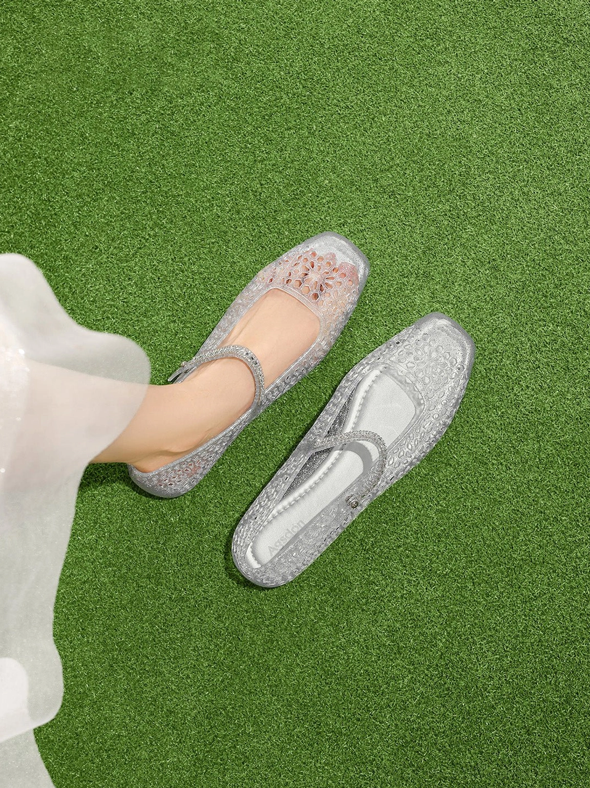 Silver glitter Mary Jane ballet flats worn with sheer white skirt showing translucent floral cutout jelly texture