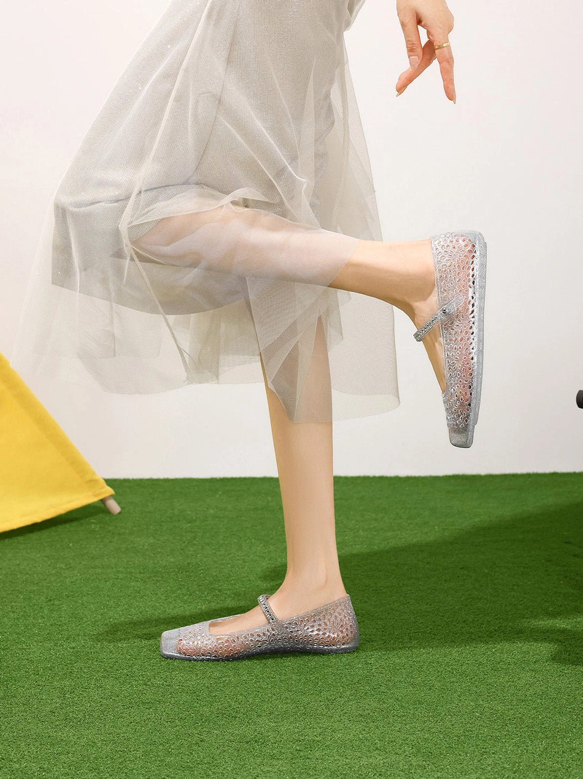Close side view of silver glitter jelly Mary Jane flats with square toe floral cutouts and buckle strap
