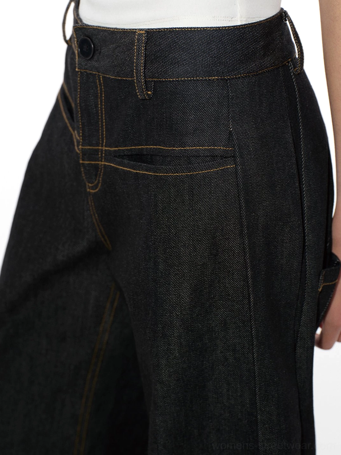 Close-up side and back detail of curved raw denim jeans with tailored waistband side seam and yellow stitched pocket