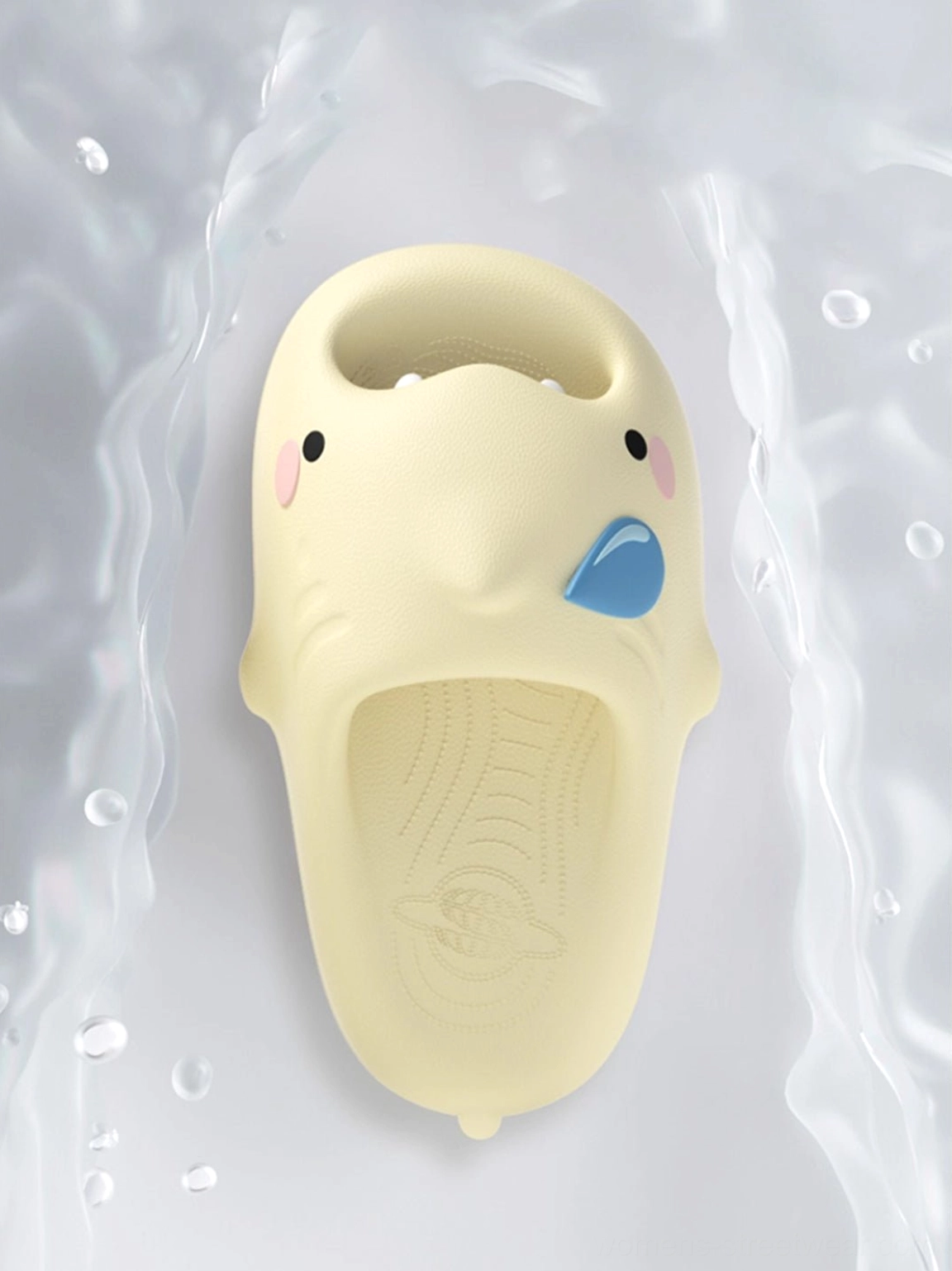 Top-down yellow cartoon shark slide slipper surrounded by water droplets showing textured footbed and character details