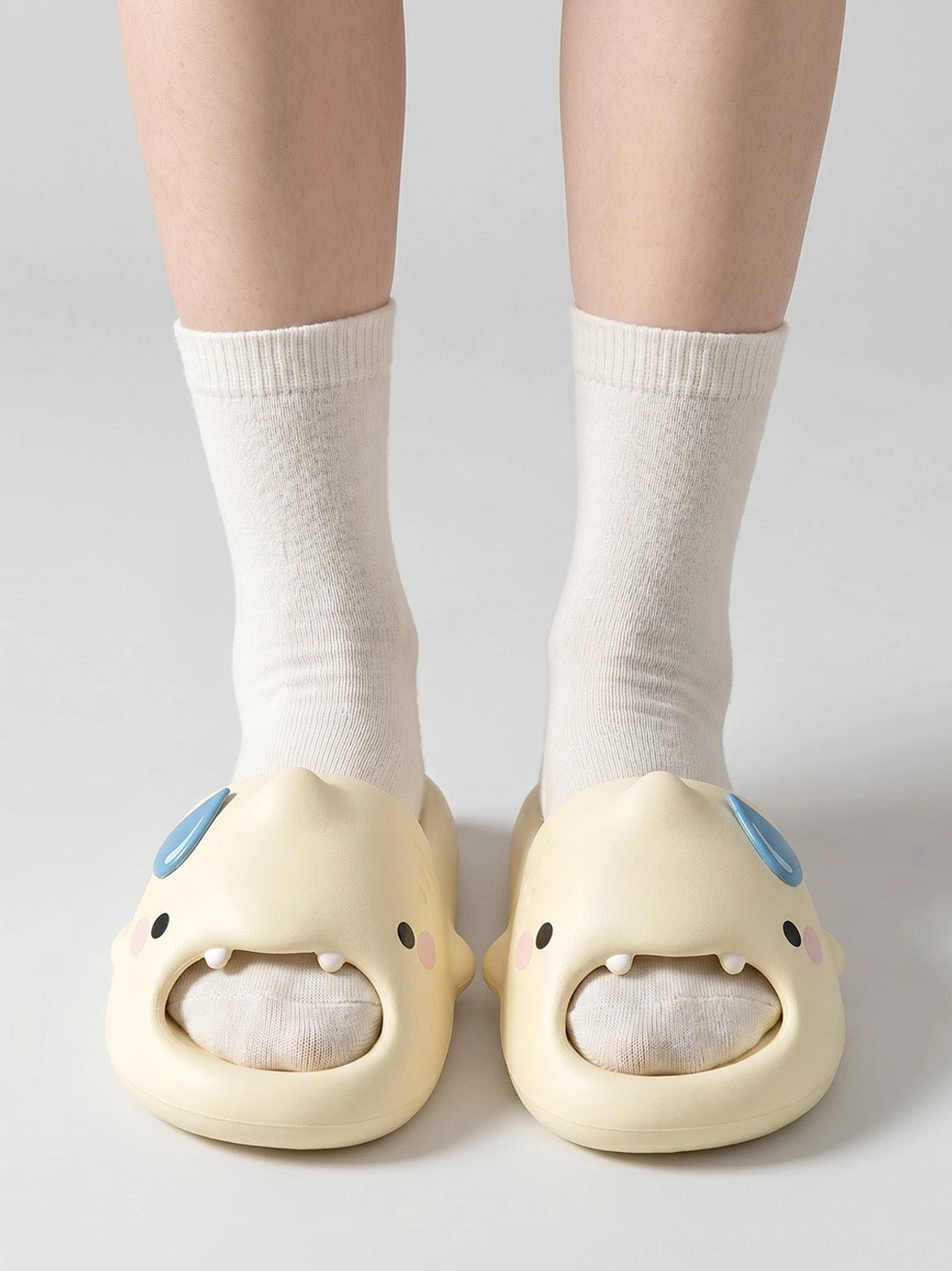 Front view of matching shark character platform slippers worn with white socks showing eyes teeth and textured footbeds