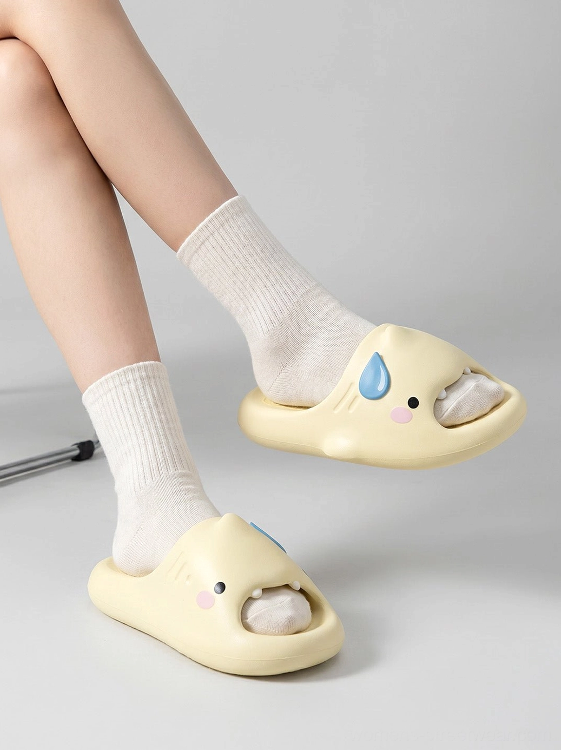 Pair of cute shark platform slide slippers worn with white crew socks in a low-angle indoor streetwear footwear view