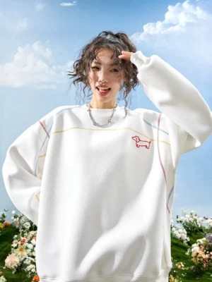 White dachshund embroidered oversized crewneck sweatshirt with red chest dog embroidery and colorful contrast stitching worn by a female model outdoors