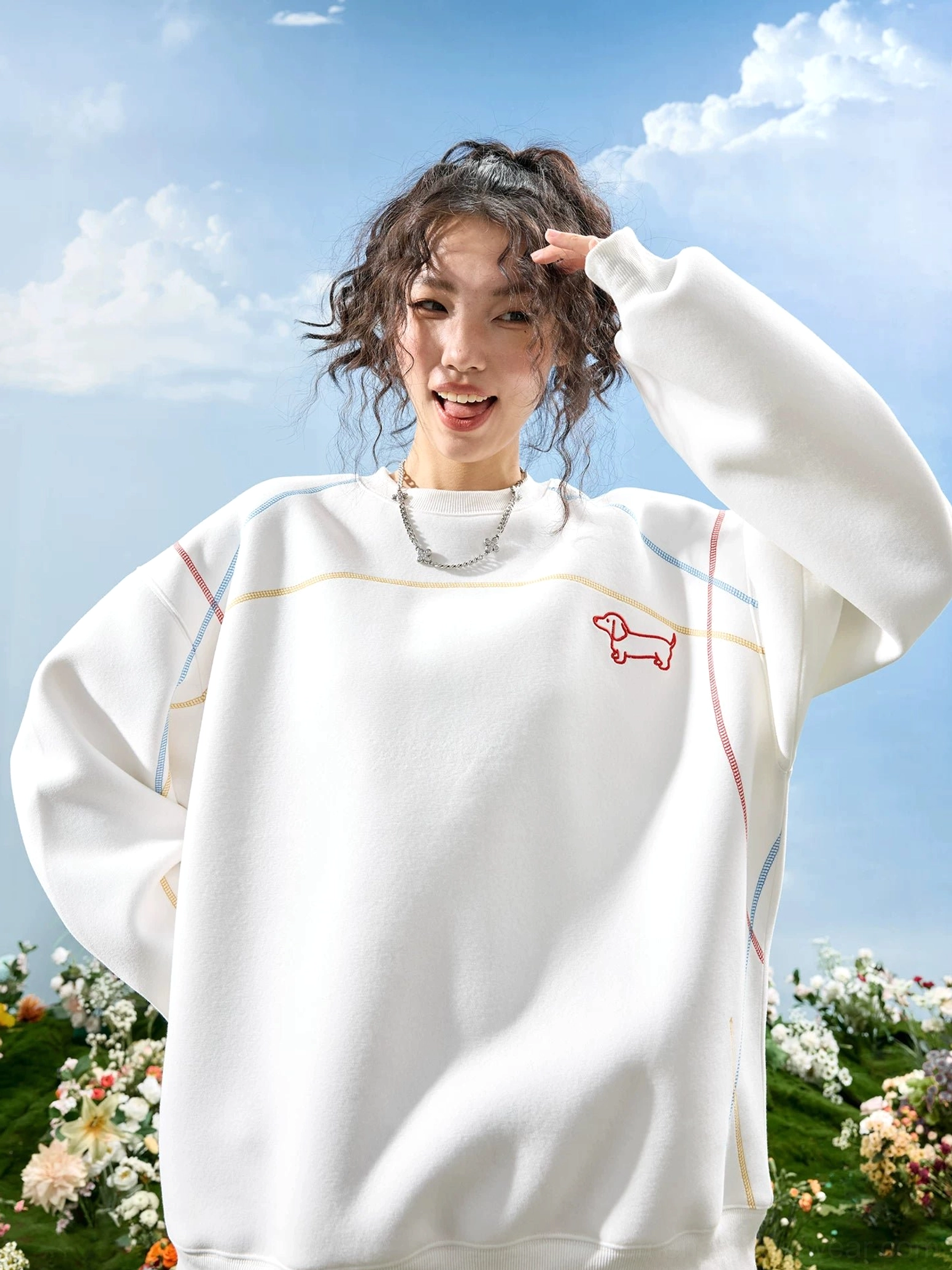 White dachshund embroidered oversized crewneck sweatshirt with red chest dog embroidery and colorful contrast stitching worn by a female model outdoors