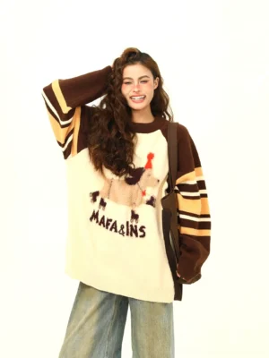 Front view of an oversized cream dachshund graphic knit sweater with brown striped raglan sleeves styled with wide-leg jeans