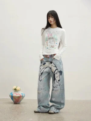 Full-body front view of a female model wearing washed blue dalmatian graphic straight-leg jeans with a relaxed oversized streetwear fit in a minimalist white studio