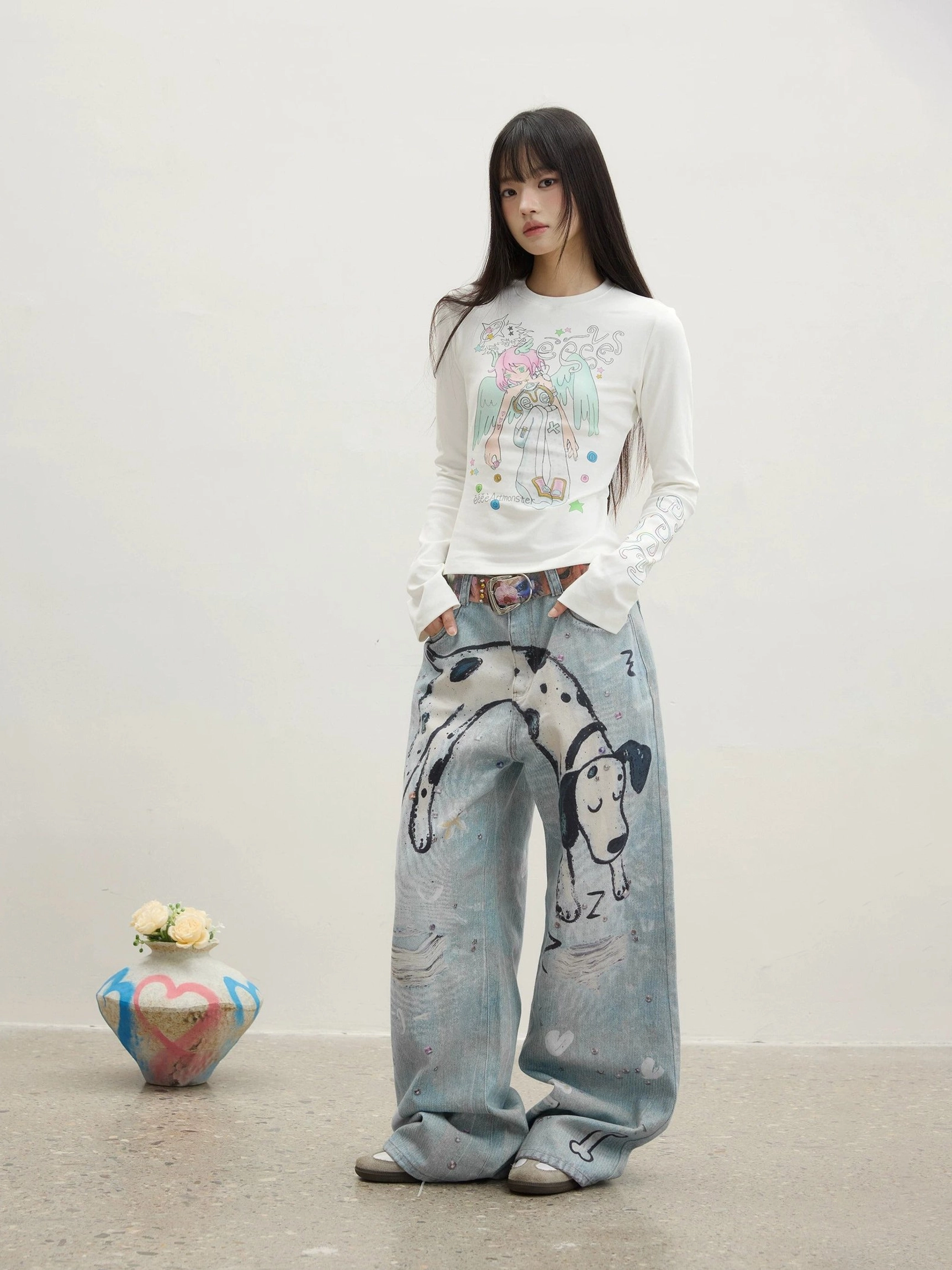 Full-body front view of a female model wearing washed blue dalmatian graphic straight-leg jeans with a relaxed oversized streetwear fit in a minimalist white studio