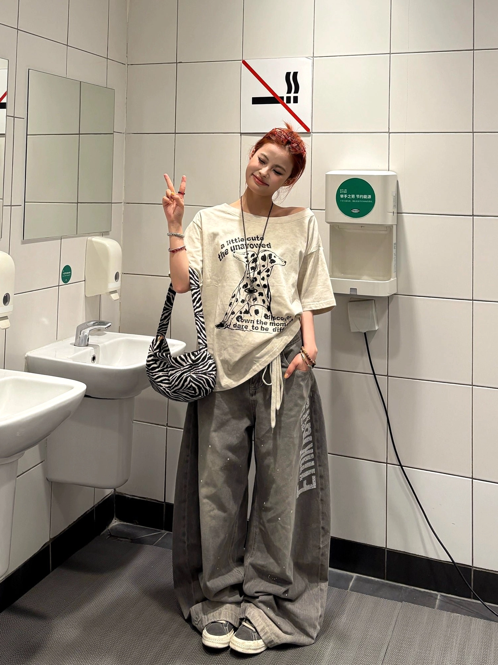 Woman wearing an apricot Dalmatian print oversized T-shirt with drop shoulders, distressed hem, wide-leg jeans and casual sneakers in a vintage streetwear outfit