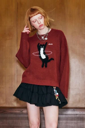 Burgundy red dancing cat jacquard knit sweater in Korean streetwear style with relaxed drop shoulders and black ruffled mini skirt