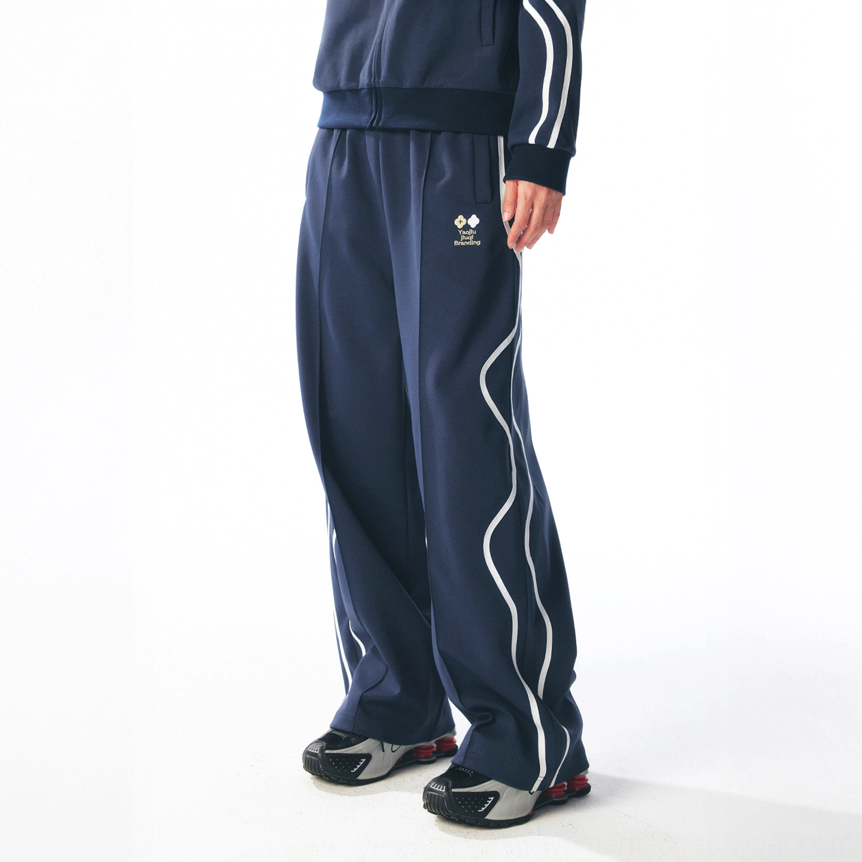 Dark blue curved stripe track pants with relaxed wide-leg silhouette styled with a matching sporty jacket