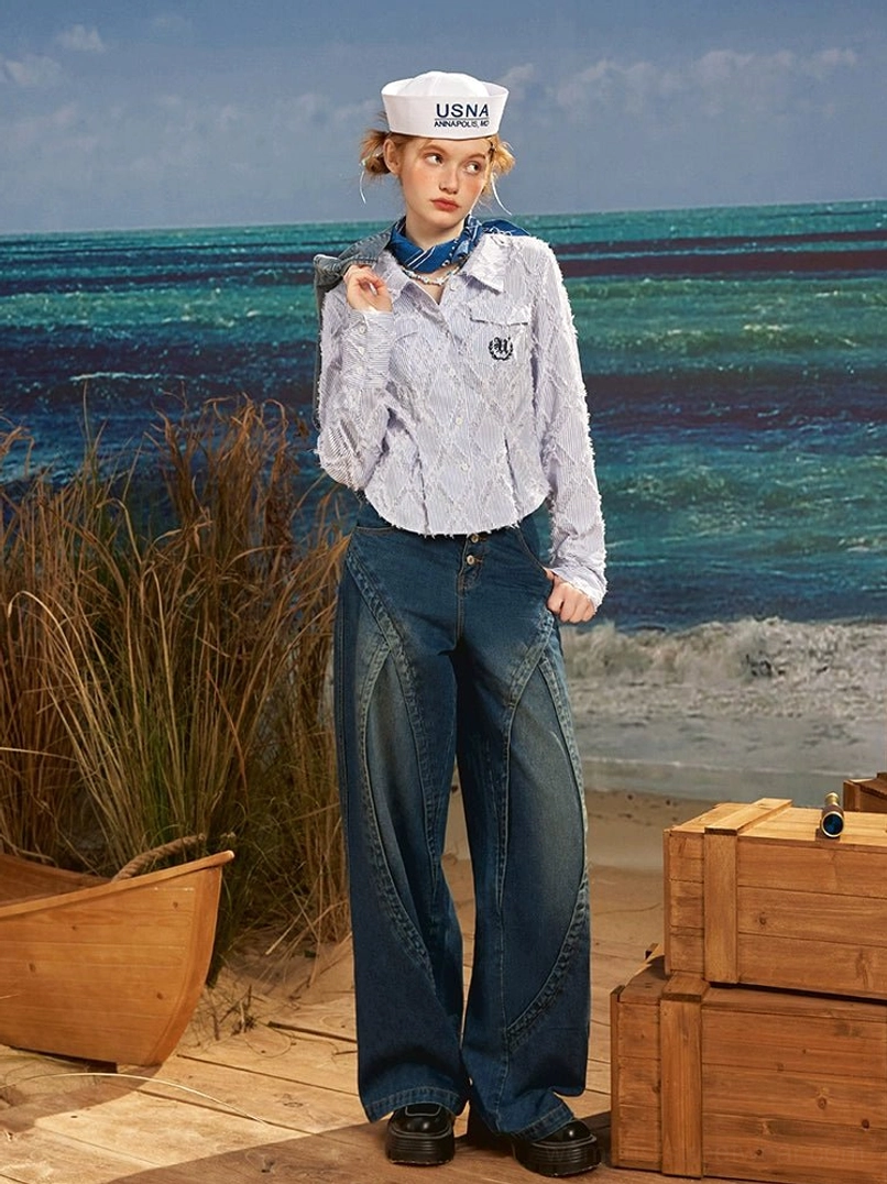 Front full body view of women's dark blue high rise wide leg jeans in structured vintage wash denim on a seaside deck