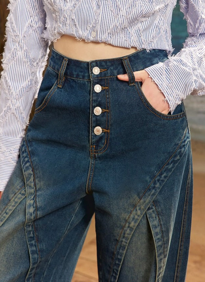 Close-up front waist detail of dark blue high rise wide leg jeans with four exposed buttons, side pocket and curved thigh seams