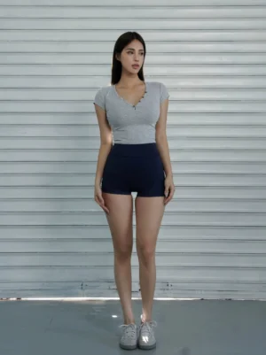 Dark blue high-waist cycling shorts shown from the front with a body-hugging stretch fit styled with a gray cropped top and white sneakers