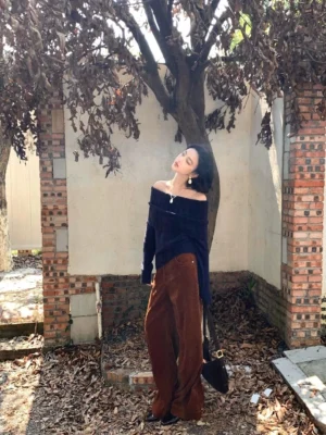 Dark blue women's off-shoulder ribbed knit sweater styled with caramel corduroy wide-leg pants in an autumn streetwear outfit