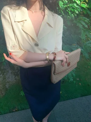 Close-up of dark blue retro knee-length pencil skirt paired with an embroidered cream blouse and vintage-inspired styling