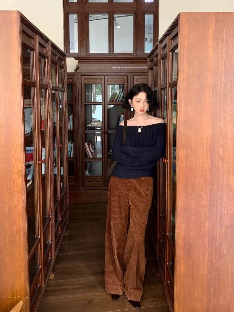 Dark blue slim fit off-shoulder knit sweater on a woman with caramel wide-leg corduroy pants in a retro streetwear outfit
