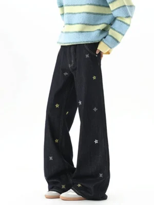 Side three-quarter view of relaxed dark blue wide-leg jeans with scattered yellow and grey star embroidery