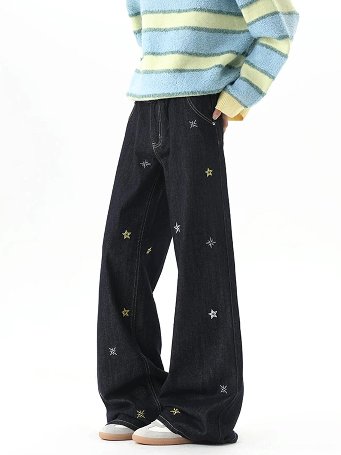 Side three-quarter view of relaxed dark blue wide-leg jeans with scattered yellow and grey star embroidery