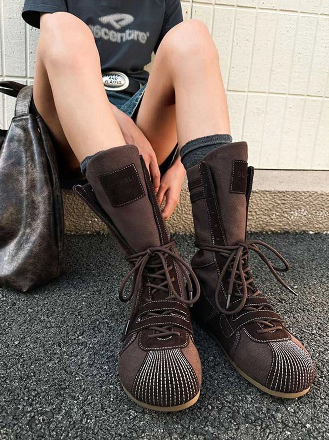 Dark brown hybrid boxing trainer boots styled with shorts and socks in an outdoor streetwear outfit