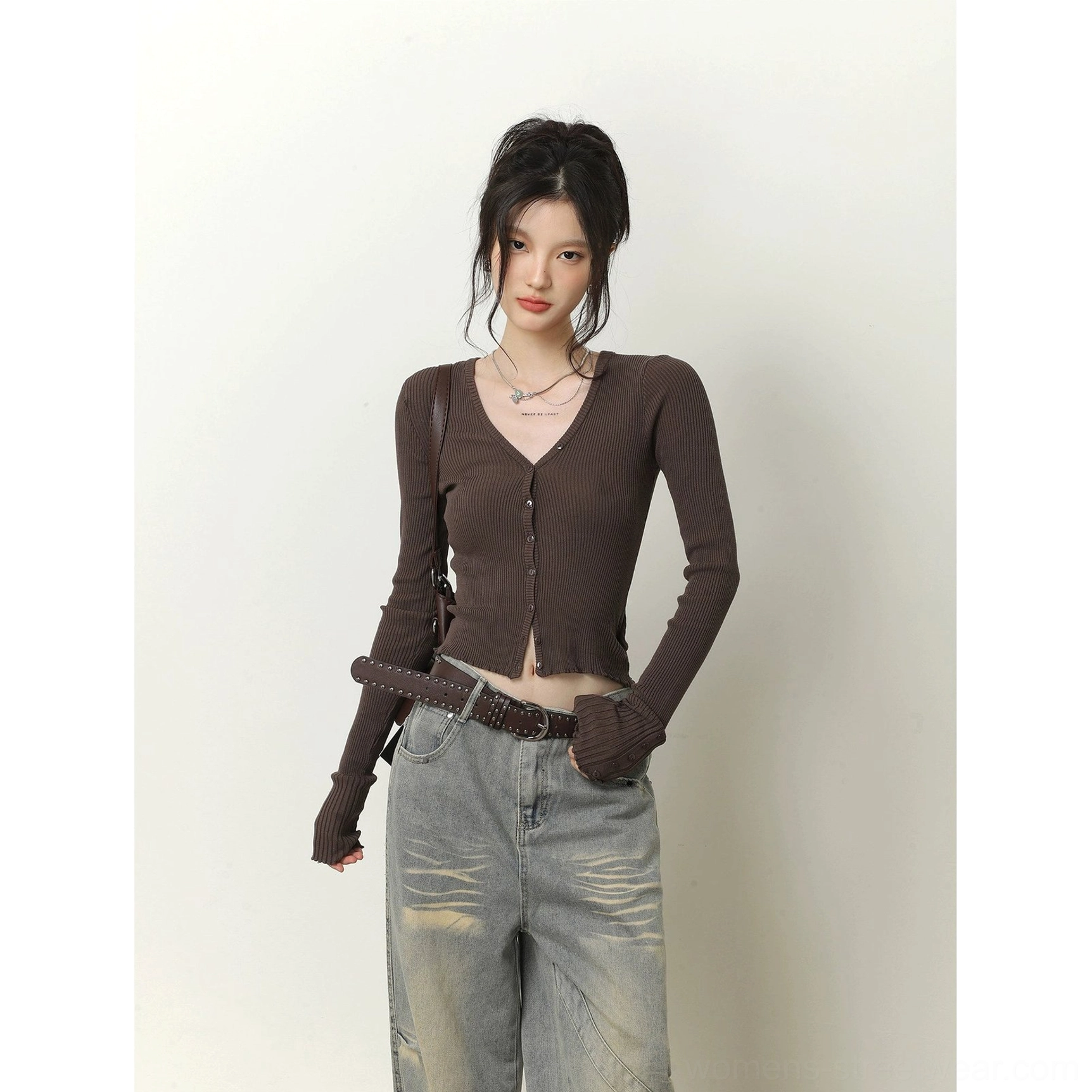 Dark brown cropped ribbed cardigan with exposed waist, fingerless sleeve cuffs, and faded gray wide-leg jeans