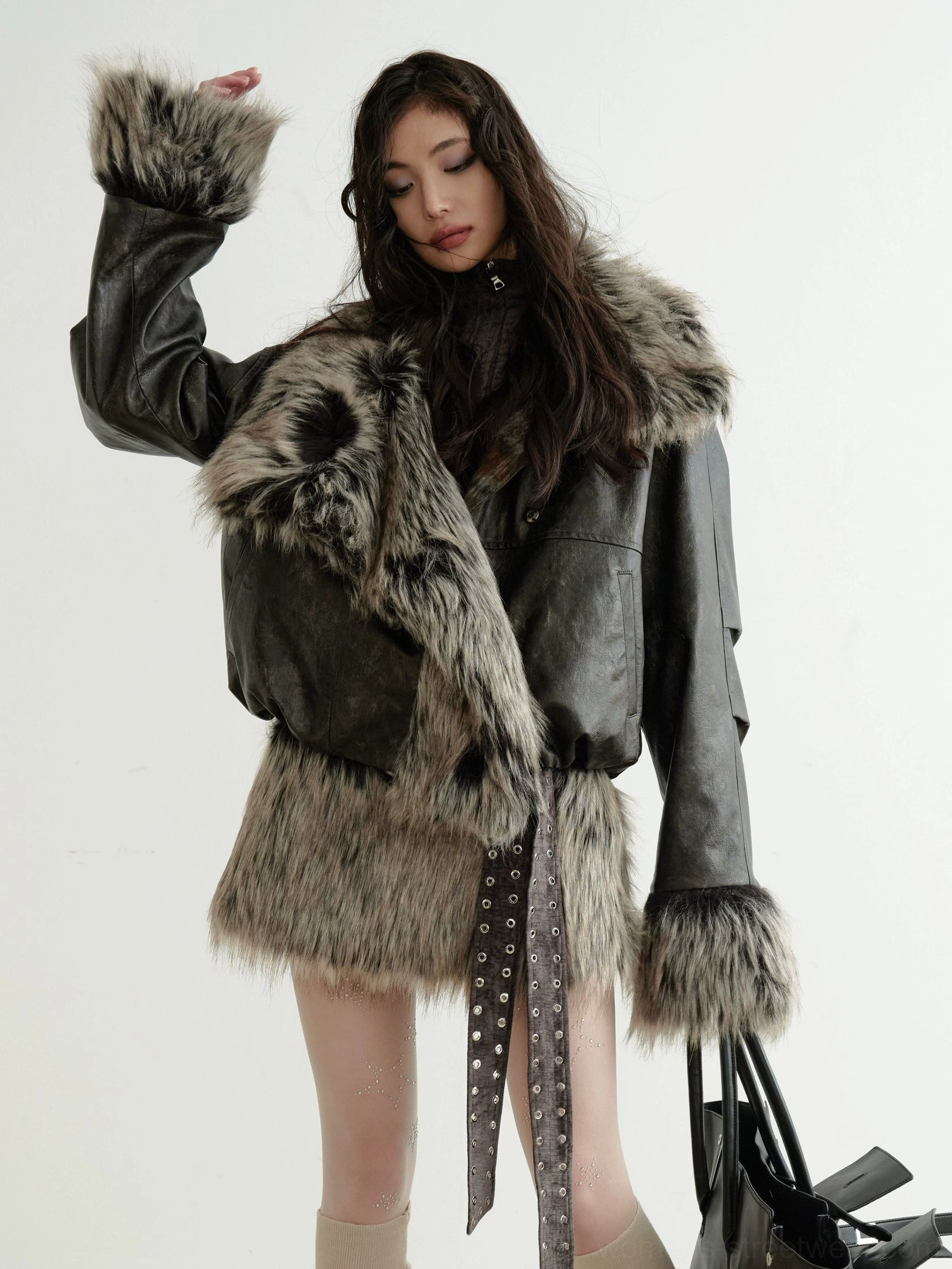 Woman wearing a dark brown faux fur collar cropped jacket with a mini skirt and decorative waist strap for a Y2K streetwear look